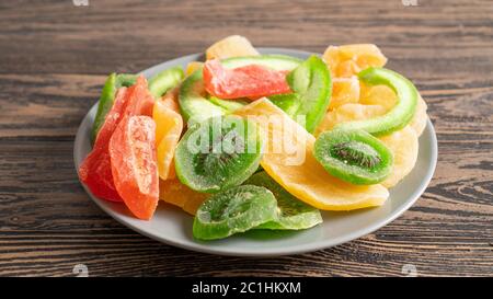Menu di cibi sani dolci colorati per bambini. Frutta secca su un piatto da vicino. Dessert dietetico su un tavolo di legno Foto Stock