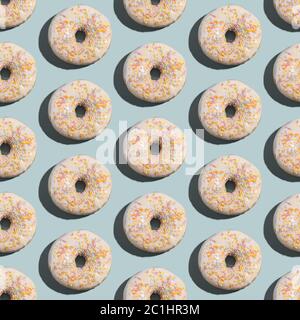 Ciambelle bianche alla vaniglia con spruzzette, dolce dessert satinato senza cuciture motivo su sfondo blu pastello Foto Stock