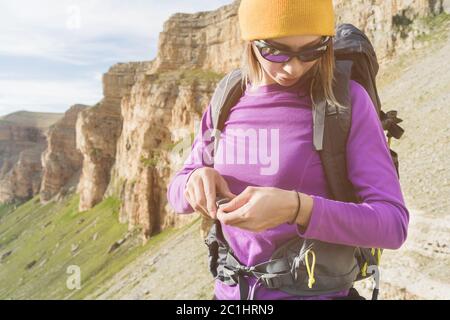 un turista in occhiali da sole mette uno zaino nella natura sullo sfondo di rocce epiche che si preparano per il trekking con l'arrampicata. Il Foto Stock