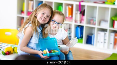 Due ragazze di scuola godono il loro spuntino sano a scuola Foto Stock