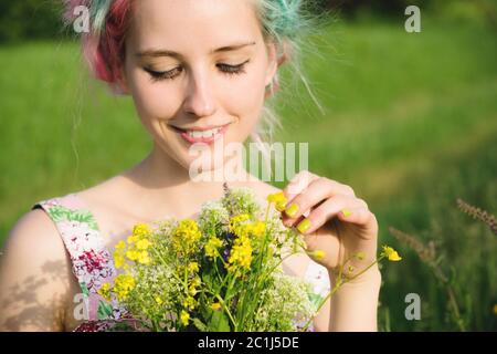 Ritratto di una giovane ragazza sorridente felice in un abito di cotone con bouquet di fiori selvatici Foto Stock