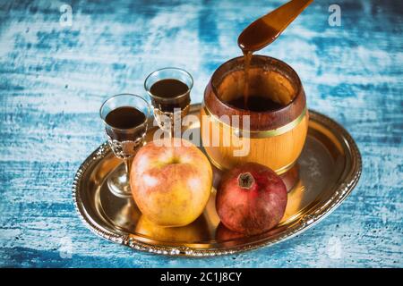 Versando il miele su apple e melograno con simboli di miele ebraica di Nuovo Anno Rosh Hashanah. Foto Stock