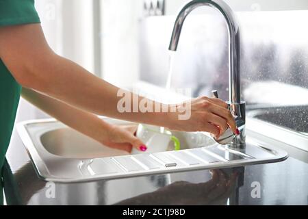 Donna che versa l'acqua nella tazza per bere in cucina Foto Stock