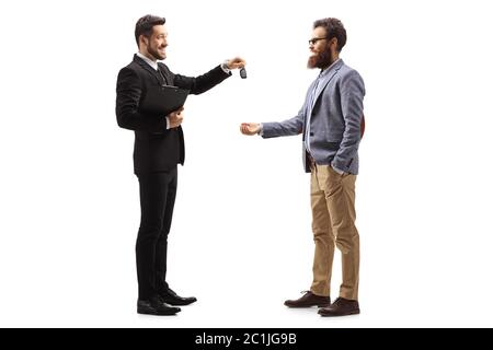 Foto di profilo a lunghezza intera di un uomo d'affari che dà le chiavi dell'automobile ad un uomo sorridente bearded isolato su sfondo bianco Foto Stock