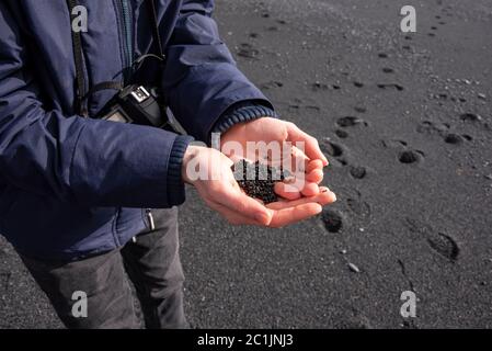 Una manciata di sabbia nera sulla spiaggia di Vik, Islanda del Sud Foto Stock