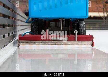 preparazione del ghiaccio alla pista pubblica tra le sessioni in serata all'aperto. Ghiaccio lucido pronto per la partita. Closeup macchina per la manutenzione del ghiaccio Foto Stock