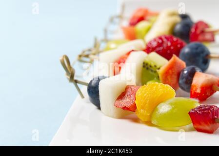 Crostini di frutta. Tartine di frutta fresca su piatto bianco. Frutta mista in piatto bianco stile alimentare sano, sfondi blu. Foto Stock
