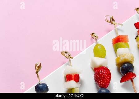 Crostini di frutta. Tartine di frutta fresca su piatto bianco. Frutta mista in piatto bianco stile alimentare sano. Sfondi rosa. Foto Stock