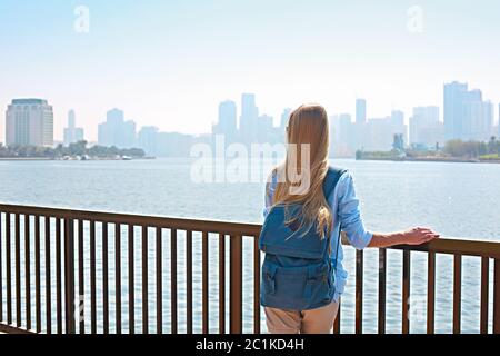 Donna turistica con zaino e panorama di Sharjah e artificiale lago, Sharjah, Foto Stock