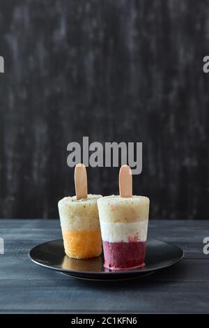 Frutta gelato al caffè per lecca-lecca su un bastone in una piastra nera su una tavola di legno scuro con tavolo spazio di copia Foto Stock