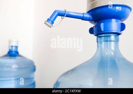 Bere acqua pulita a casa. Primo piano vista del rubinetto del grande meccanismo blu della bottiglia del radiatore della pompa per uso in casa o in ufficio. Due bottiglie per la salute Foto Stock