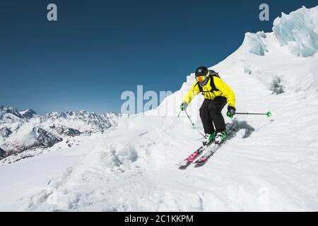 Sciatore professionista alla velocità prima di saltare dal ghiacciaio in inverno contro il cielo blu e le montagne Foto Stock