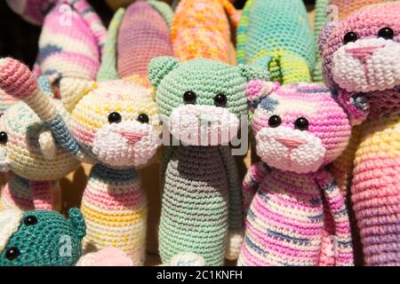 i giocattoli a maglia cute gattino lavorato a maglia siedono insieme con altri giocattoli a crochet sul mercato del fine settimana. Foto Stock