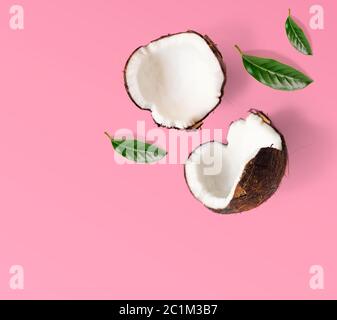 Layout creativo fatto di noci di cocco e foglie. Disposizione piatta. Concetto di cibo. Cocco su sfondo rosa. Foto Stock