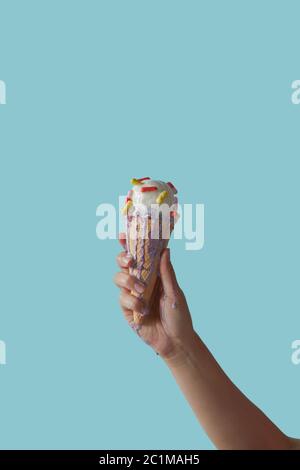 Una mano femminile tiene il gelato con pillole su sfondo blu. Spazio di copia. Foto Stock