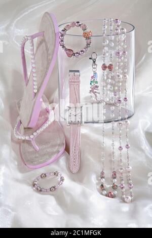 ancora vita di collana rosa catene orologio e infradito flop su sfondo satinato bianco Foto Stock