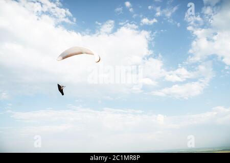 Parapendio da solo che vola nel cielo blu sullo sfondo delle nuvole. Parapendio nel cielo in una giornata di sole Foto Stock