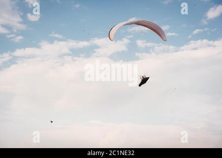 Parapendio da solo che vola nel cielo blu sullo sfondo delle nuvole. Parapendio nel cielo in una giornata di sole Foto Stock