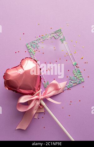 Concetto di San Valentino. Layout creativo con palloncino in cuori valentini con fiocco di nastro rosa e certificato di carta trasparente bianco con verde Foto Stock