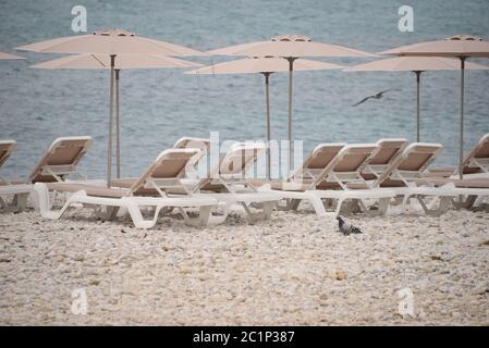 Sedie a sdraio e grandi, piccole, pietre rotonde sul Mediterraneo nella provincia di Alicante, Spagna Foto Stock