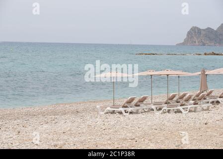 Sedie a sdraio e grandi, piccole, pietre rotonde sul Mediterraneo nella provincia di Alicante, Spagna Foto Stock