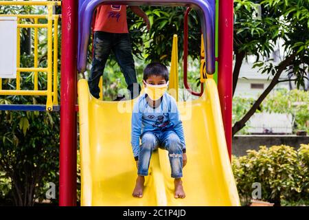 Un ragazzo piccolo che gioca in un parco mentre indossa una maschera dopo il blocco di covid19 è stato sollevato in India Foto Stock