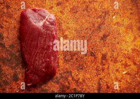 Pezzo di carne di manzo fresca grezza posto su fondo arrugginito Foto Stock