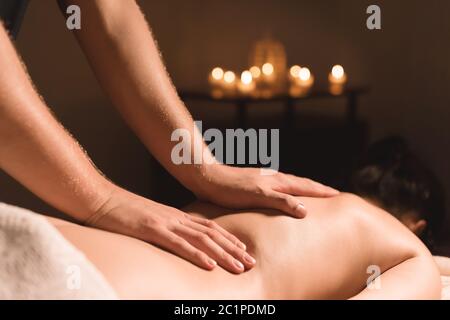 Primo piano delle mani maschili. Massaggiatore fa massaggio per la vita di una ragazza giovane. Riabilitazione, terapia di bellezza medicina Foto Stock