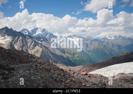 Paesaggio montano polveroso e sporco pendio vulcanico con un ghiacciaio che si scioglie incrinato sullo sfondo delle montagne del Caucaso. Glo Foto Stock
