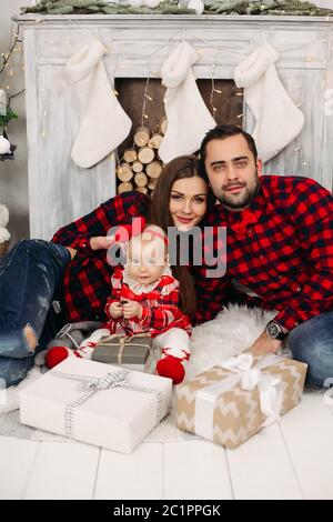 Famiglia con bambino bello ragazza con presenta al camino. Foto Stock