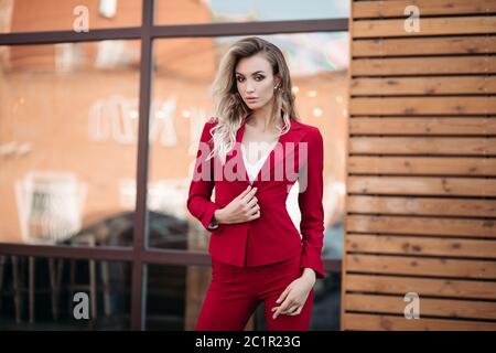 Eleganti Donna bionda in rosso scuro Tuta con bottoni oro. Foto Stock