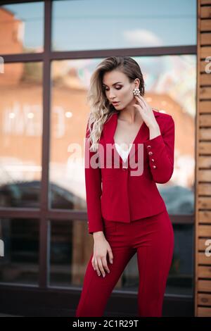 Eleganti Donna bionda in rosso scuro Tuta con bottoni oro. Foto Stock