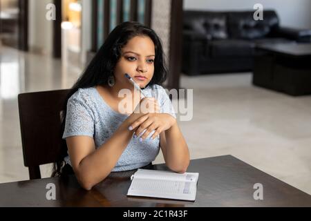 Una donna indiana ha perso nei pensieri come scrive nel suo diario Foto Stock