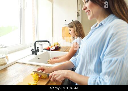 Bella bambina con la madre in cucina che prepara un'insalata di frutta Foto Stock