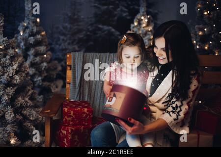 Felice amorevole madre con bambino guardando all'interno di regalo di Natale Foto Stock
