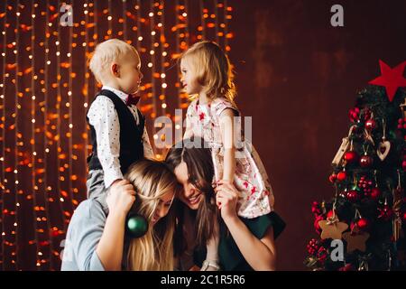 Due madri seduta con simpatici ragazzi regali di Natale. Foto Stock