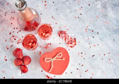 Bottiglia di champagne di rose, bicchieri con fragole fresche e a forma di cuore dono Foto Stock