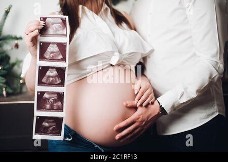 Raccolto di donna incinta che posa con l'uomo, tenendo immagini ecografiche. Foto Stock