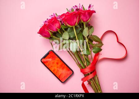 Bouquet di rose rosa con arco a forma di hart e telefono cellulare con schermo di copia Foto Stock