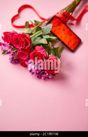 Bouquet di rose rosa con arco a forma di hart e telefono cellulare con schermo di copia Foto Stock