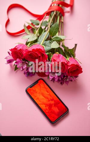 Bouquet di rose rosa con arco a forma di hart e telefono cellulare con schermo di copia Foto Stock