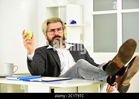 Concetto di crisi. Uomo di successo imprenditore formale di affari seduta ufficio interno. Il manager aziendale si rilassa. Lavoro in ufficio. Concetto aziendale. Hipster giocare palla da tennis. Burnout e mancanza di idee. Foto Stock