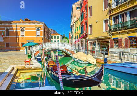 Venezia con gondola e motoscafi ormeggiati sullo stretto canale Rio dei Frari, edifici colorati e ponte di pietra, Regione Veneto, Italia settentrionale, cielo blu di fondo in estate Foto Stock