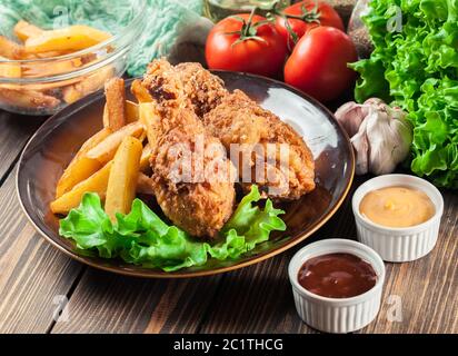 Cosce di pollo fritte del kentucky croccanti con patatine fritte in un piatto Foto Stock