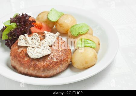 Cotoletta di carne con patate bollite e verdure su un piatto bianco. Foto Stock