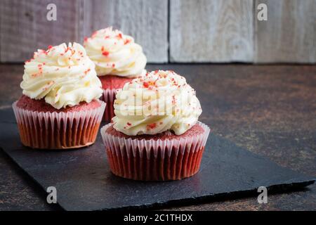 Cupcakes rosso velluto su tavola di ardesia su sfondo scuro della tavola di pietra. Dessert per le feste Foto Stock