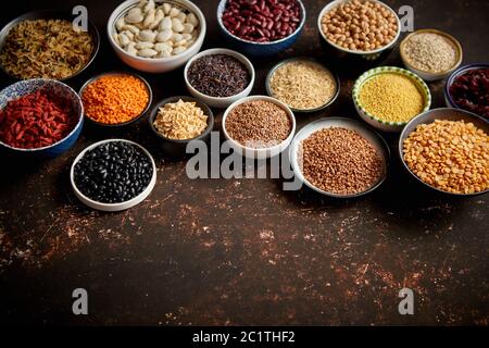 Varie superfoods in piccole ciotole scuro su sfondo arrugginito Foto Stock