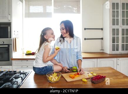 Bellissima bambina con la madre in cucina preparare una macedonia di frutta fresca Foto Stock