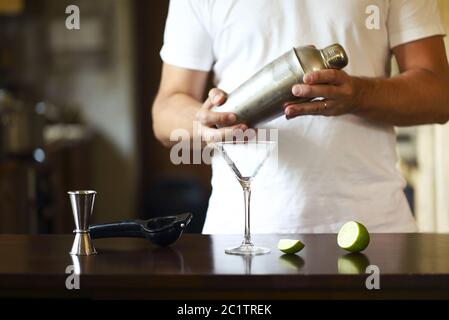 Barman al lavoro, preparazione di cocktail. Versare martini al bicchiere da cocktail Foto Stock
