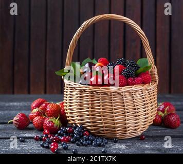 Mix di frutti di bosco in cesto su rustico sfondo di legno Foto Stock